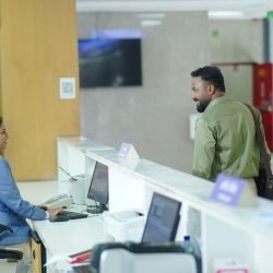 A receptionist assists a guest at the reception desk in a modern hotel lobby in Dhaka, Bangladesh.